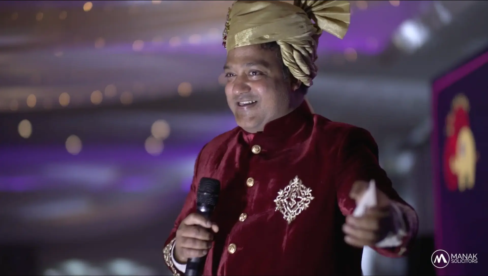A Big Jalebi performer in a red sherwani holding a microphone